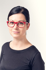 Fototapeta premium Portrait of a young woman with black hair and red glasses.