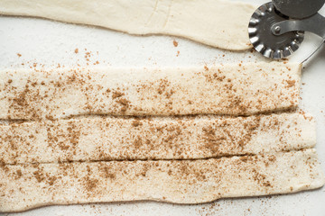 rolled strips of dough for pies strudel or cookies, sugar cinnamon flour around curly knife for...