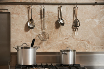 Two new metal saucepan in the kitchen in gas hob. Elegant kitchen studio interior for cooking with...