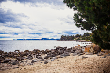 Fototapeta na wymiar deserted beach in Hobart, Tasmania with rocks in the foreground
