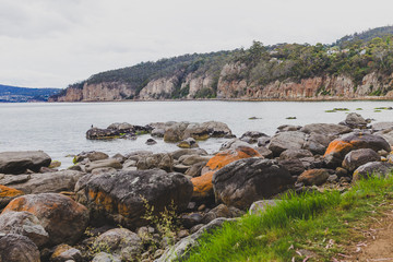 deserted beach in Hobart, Tasmania with rocks in the foreground