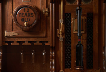 Vintage old wine barrel cabinet with bottle of red wine, close-up