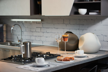 Delicious croissant and a two cup of coffee on a kitchen counter. Healthy breakfast with coffee in sunny morning for two person in modern kitchen interior