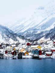 wooden houses on the banks of the Norwegian fjord, beautiful mountain landscape in winter