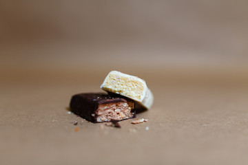 Closeup protein bar in the cut on the baking paper, Teflon paper, Diet snacks, sports nutrition. Whey protein powder and chocolate protein bar on wooden background.