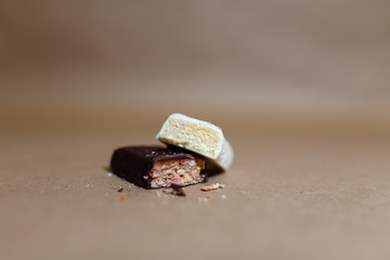 Closeup protein bar in the cut on the baking paper, Teflon paper, Diet snacks, sports nutrition. Whey protein powder and chocolate protein bar on wooden background.