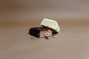 Closeup protein bar in the cut on the baking paper, Teflon paper, Diet snacks, sports nutrition. Whey protein powder and chocolate protein bar on wooden background.