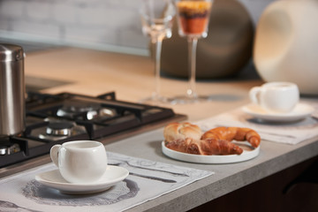Delicious croissant and a two cup of coffee on a kitchen counter. Healthy breakfast with coffee in sunny morning for two person in modern kitchen interior