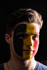 Face portrait of happy fan support Belgium national team with painted face isolated on dark background
