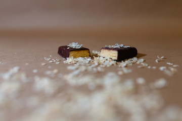 Closeup protein bar in the cut sprinkled with rice flakes on the baking paper, Teflon paper, Diet snacks, sports nutrition. Whey protein powder and chocolate protein bar on wooden background.