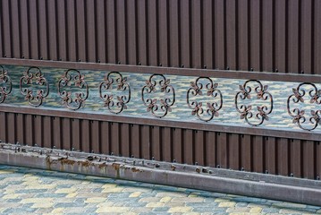 part of the brown iron gate with a pattern on the street above the sidewalk