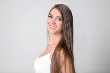 Obraz na płótnie Canvas Portrait of young woman with long beautiful hair on light background