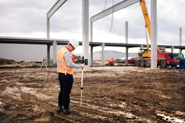 Surveyor engineer working on construction site, working with theodolite and gps system