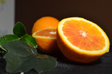 A juicy, beautiful orange with a leaf lies on a table