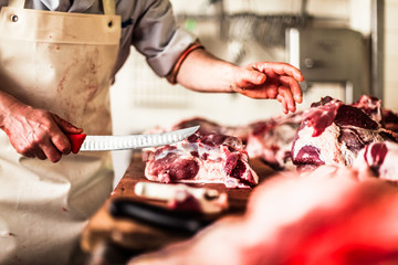 butcher cut raw meat with a knife at table in the slaughterhouse