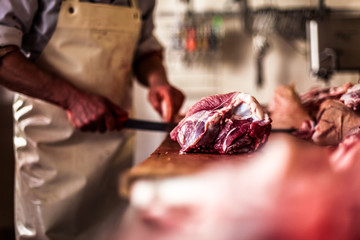 butcher cut raw meat with a knife at table in the slaughterhouse