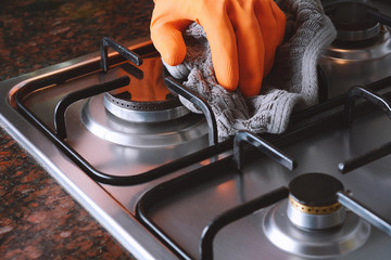 Close up view of hands in rubber gloves cleaning hob