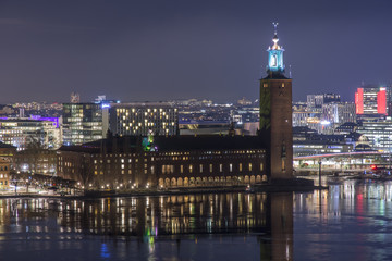 Fototapeta na wymiar Stockholms Stadshus Tre kronor fotat en klar natt med Stockholms city i bakgrunden till höger