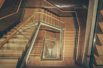 Spiral staircase from above with parquette floor. Square shaped stairs going downwards creating...