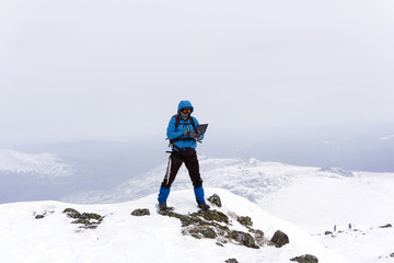 traveller freelancer works with a laptop in the winter in the wild mountains away from civilization