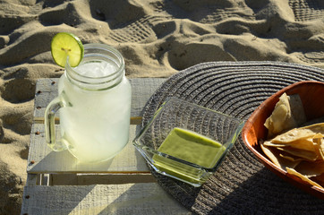 snack of green salsa, tortilla chips, lemonade at the seashore beach