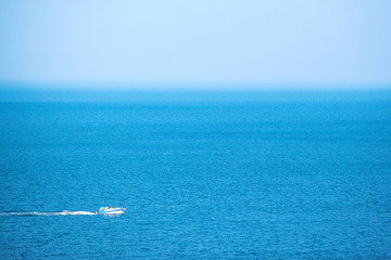 Obraz premium a small solitary white yacht sails in the middle of the blue sea