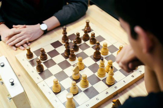 Pensive teenager play chess during chess competition in chess club. Education, chess and mind games. 
