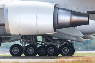 Closeup of landing gear of passenger wide-body airplane on runway, side view