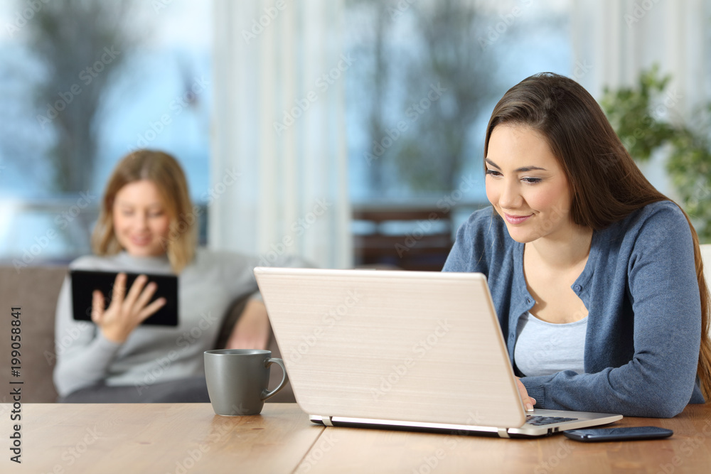 Poster Two relaxed roommates using multiple devices at home