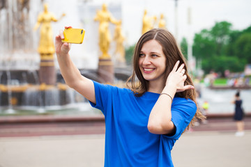 Smiling woman take a picture of herself with a smartphone. Selfie