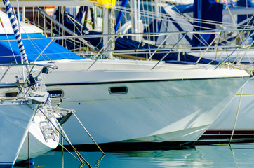 closeup on a yacht, yachts and motor boats anchored in a harbor, a hot day and blue water in a...