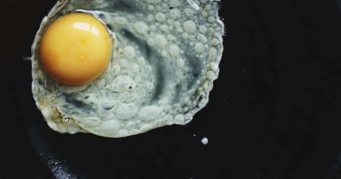 Slow motion shot of egg being dropped on hot pan