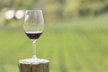 Wine in a wine glass on a post at a winery in a field