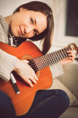 Young woman playing guitar at home. Relaxed happy young woman with music instrument portrait