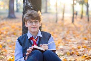 Wizard, Magic Wand, cute boy outdoor is reading book and spelling incantations in the autumn park....