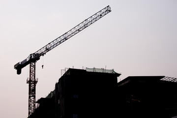 silhouette The construction of the building by using crane construction equipment transporter