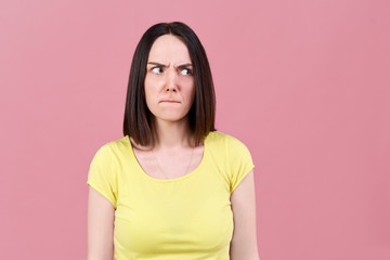 Fototapeta premium dark-haired girl resentfully inflated her lips and looks irritably to the side, frowning her eyebrows.