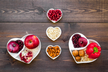 Food which help heart stay healthy. Vegetables, fruits, nuts in heart shaped bowl on dark wooden...
