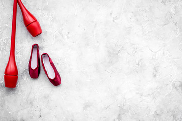 Beauty sport for girls concept. Maces for rhythmic gymnastics and ballet shoes on grey background top view copy space