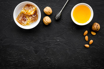 Fresh honey as dessert. Honey in bowl, honeycomb, nuts on black table top view copy space