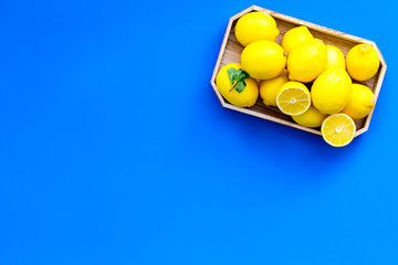 Ripe lemon fruit in tray on blue background top view copy space
