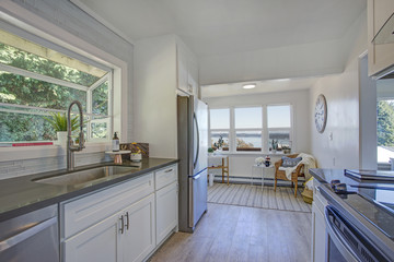 White kitchen with light filled sitting area.