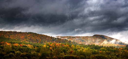 Panorama of a Vermont hillside on a foggy day during peak fall foliage season