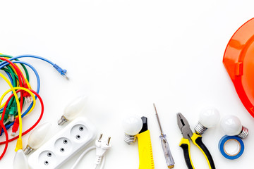 Electrician work concept. Hard hat, tools, cabel, socket outlet on white background top view space for text