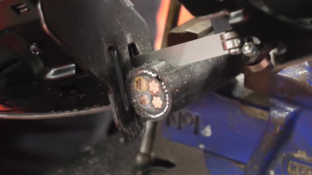 Close up view of power saw jigsaw cutting a piece of electric cable