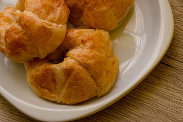 Croissants pastry on the wooden table. The croissants is a bread product made of a layered yeast-leavened dough with butter rolled and folded several times in succession, then rolled into a sheet.