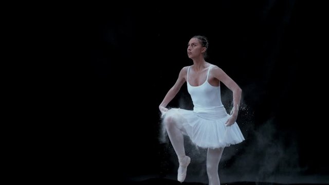 Ballerina performing on black background spinning slow motion