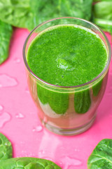 Glass with Green Fresh Smoothie from Leafy Greens Vegetables Fruits. Apples Bananas Kiwi Zucchini Scattered Spinach Leaves on Fuchsia Pink Background with Water Drops. Healthy Lifestyle Detox Vitamins