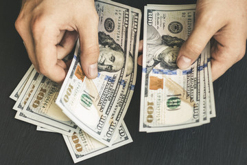 The white young man counts the money, one hundred new dollar bills on a black background close plan. Concepts of business and finance. top view .