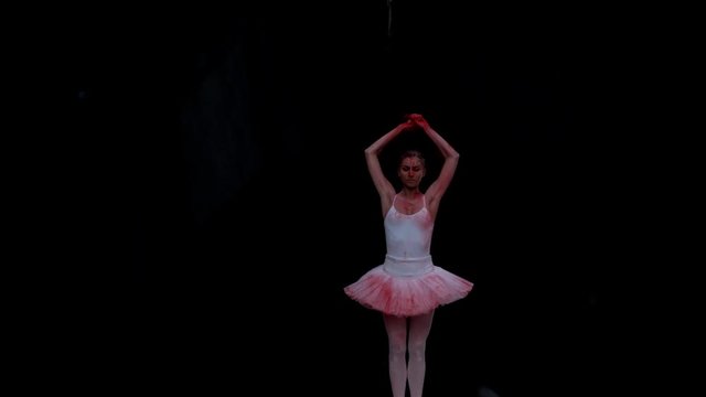 Ballerina performing on black background spinning slow motion